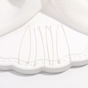 Dettaglio macro di spilli a T in argento S925 su piatto di ceramica per gioielli DIY