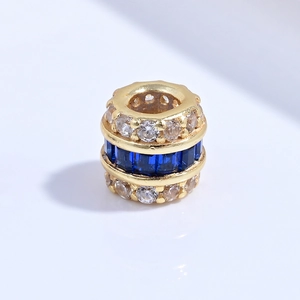 Macro detail of S925 silver cylinder bead charm with blue crystals and gold plating