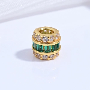 Macro shot of S925 silver barrel bead with green rectangular gems and white zircons