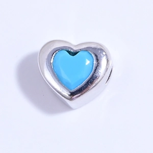 Vista macro de cuenta de corazón de plata S925 con esmalte azul vibrante y acabado pulido