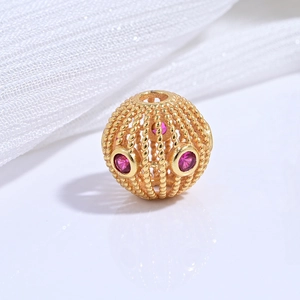 Macro shot of gold-plated S925 silver hollow bead with intricate red gemstone inlay