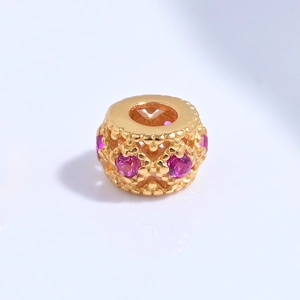 Macro detail of gold plated S925 silver hollow heart bead with pink crystal inlay