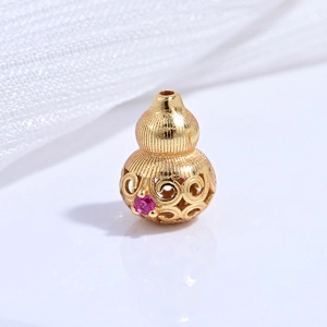 Macro detail of a hollow gold-plated s925 gourd bead with pink gemstone and floral carving