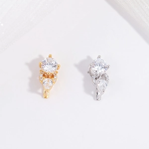 Dettaglio di orecchini a goccia in argento e oro con zirconi scintillanti su sfondo bianco