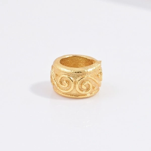 Close-up of golden S925 silver cylinder bead with engraved spiral vintage patterns
