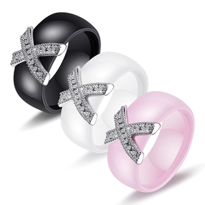 Close-up of ceramic rings in black, white and pink with X-shaped zircon-paved metal inlay