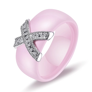 Detailed view of pink ceramic ring featuring a silver X-shaped zircon-encrusted decoration