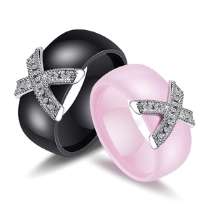 Detailed view of black and pink ceramic rings with crisscross zircon X design on white background
