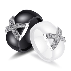Detail of wide black and white ceramic couple rings with X-shaped zircon setting