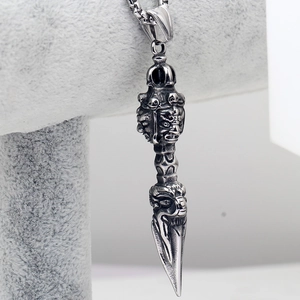 Macro shot of silver stainless steel Phurba pendant with detailed deity relief carving