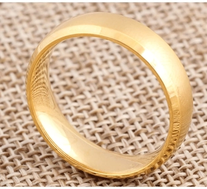 Vue macro d'une bague de 6 mm en acier titane doré poli sur fond de lin beige naturel
