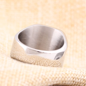 Detalle macro de anillo cuadrado plateado con textura cepillada y bordes pulidos