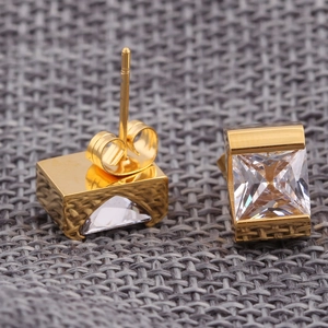 Detail of 7mm square gold-plated stud earrings with clear zircon stones on grey fabric