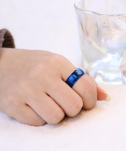 Dettaglio anello in acciaio blu spazzolato con logo massonico inciso a laser su superficie