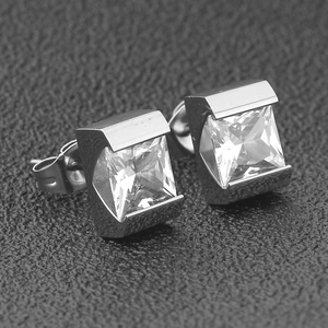 Macro view of square-cut clear gemstone earrings with tension setting on black surface