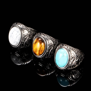Vintage stainless steel rings with turquoise, tiger eye, and white stones on black background