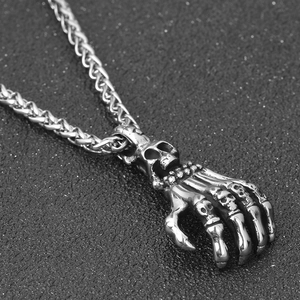 Detailed view of punk skeleton hand pendant with small skull accents on wheat chain