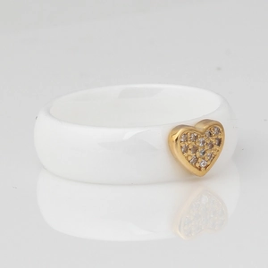 Macro detail of white ceramic ring featuring a golden heart inset with sparkling zirconia
