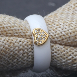 Detailed macro view of white ceramic ring featuring a golden heart inset with micro zircons