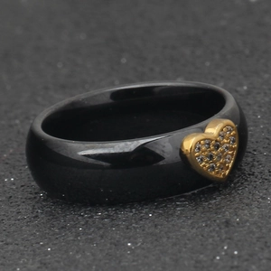 Close-up of black ceramic ring featuring a gold heart inlay with micro-pave zircons