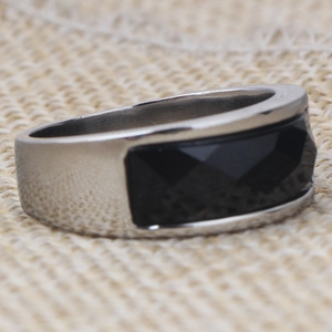 Macro side view of a minimalist stainless steel ring featuring a black faceted gemstone
