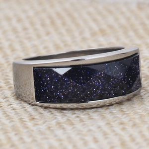 Macro shot of silver stainless steel wide ring featuring faceted blue goldstone inlay