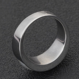 Detail view of a minimalist silver stainless steel ring on a textured black surface