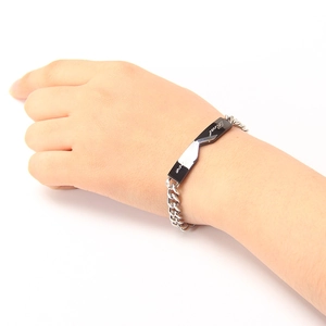 Nahaufnahme der Titanstahl-Paararmband mit Real Love Gravur auf schwarz-silbernem Stab