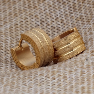 Nahaufnahme goldene 7mm Creolen mit mattiertem Finish und dreifach Rillen auf Sackleinen