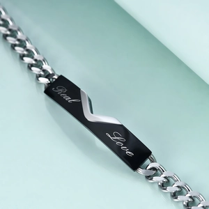 Makroaufnahme vom 5mm Edelstahlarmband mit Real Love Gravur auf schwarzer Platte
