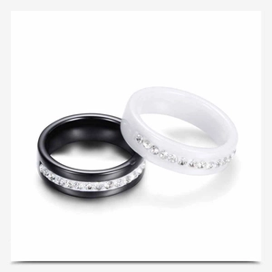 Macro detail of high-polish ceramic rings in black and white with single row crystal inlay