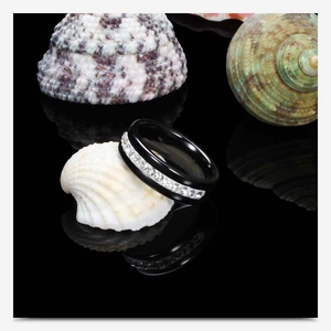 Detailed macro view of black ceramic ring with single row of white crystals on mirror base