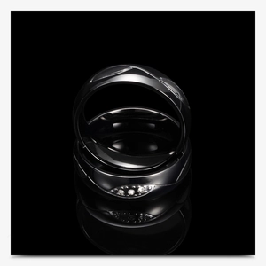 Primer plano de anillos de pareja de acero inoxidable negro con detalle de hoja de circón