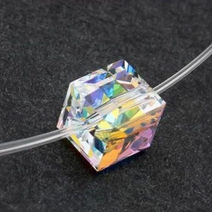 Macro shot of a faceted cube crystal bead with colorful AB coating on a clear fishing line