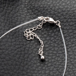 Detailed close-up of silver-plated lobster clasp and extension chain on clear line necklace