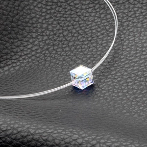 Macro detail of aurora crystal cube pendant on invisible nylon thread necklace