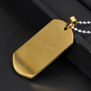 Close-up of a gold rectangular military dog tag on a silver bead chain with leather background