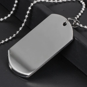 Macro detail of polished stainless steel dog tag with bead chain on black textured background