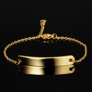 Polished 7mm golden stainless steel bar bracelet with heart charm on black background