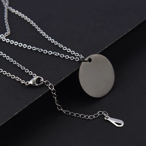 Close-up of silver stainless steel round pendant with lobster clasp and extension chain