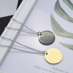 Detail view of 25mm round matte black and gold pendants on stainless steel chains