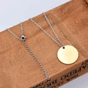 Polished gold round pendant with silver chain on wood box with lobster clasp detail