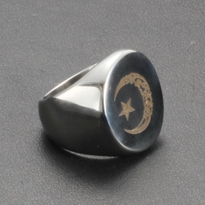 Detailed view of sun and moon laser engraving on wide stainless steel oval ring surface