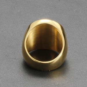 Top view of wide gold stainless steel ring with polished surface on a grey background