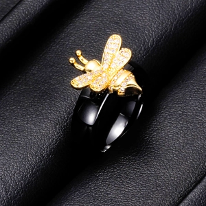 Detalle macro de un anillo de cerámica negra de 6mm con abeja dorada y circonitas brillantes