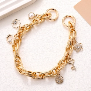 Detailed close-up of gold chunky chain with star, pearl and rhinestone charms
