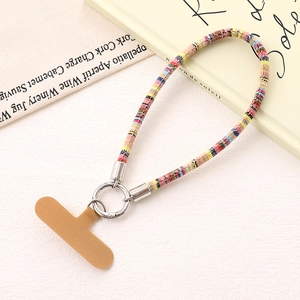 Detail of colorful woven phone wrist strap with silver metal ring and brown attachment card