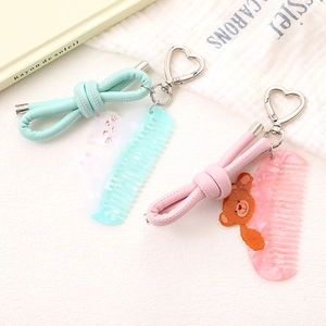 Detailed close-up of cute cartoon comb keychains with bear and cat charms on white texture