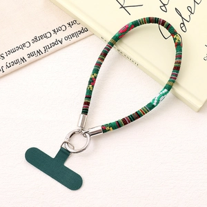 Detailed view of bohemian style woven phone wrist strap with dark green fabric patch