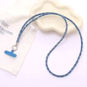 Detail of denim phone lanyard with silver sequins and metallic ring on textured fabric